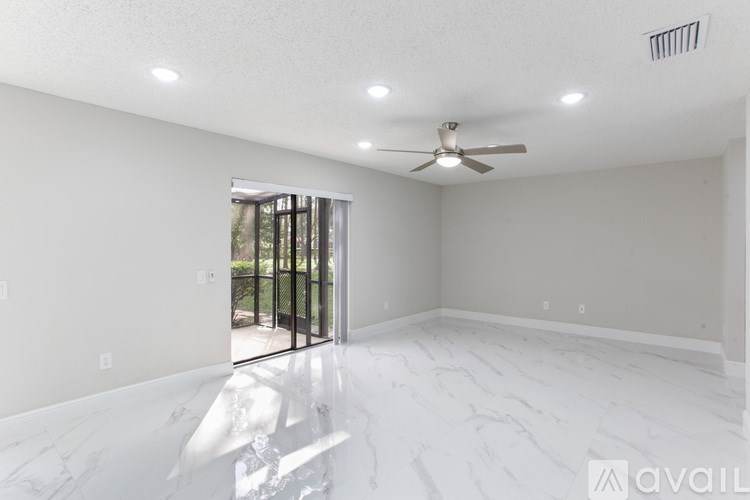 A room with a carpeted floor, a chandelier, and a window with curtains.