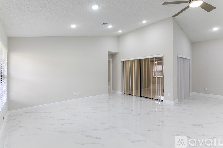 A spacious room with a marble floor and a ceiling fan.