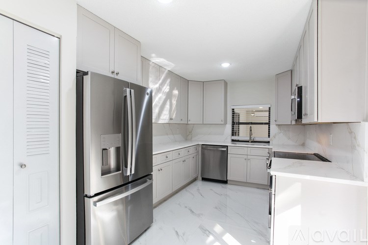 A modern kitchen with a stainless steel refrigerator and white cabinets.