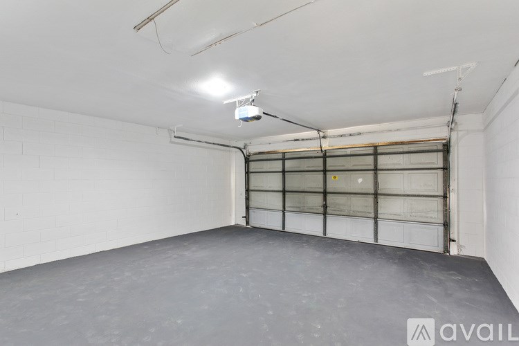 A large, empty garage with a closed door and a light on the ceiling.