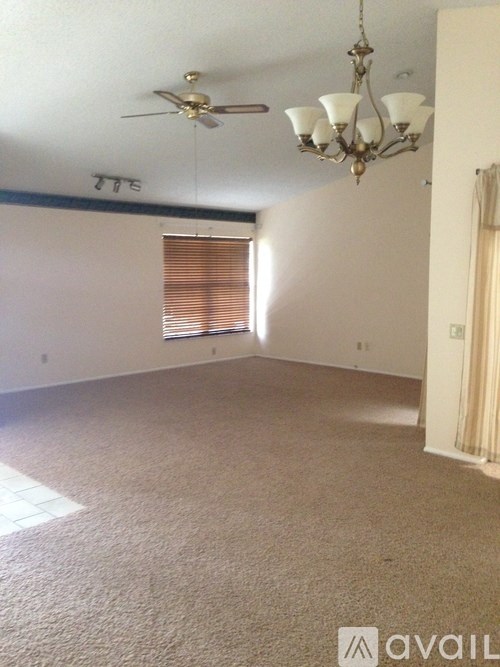A room with a carpeted floor and a chandelier hanging from the ceiling.