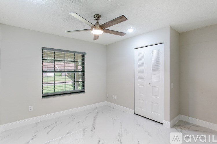 A room with a ceiling fan and a window with blinds.