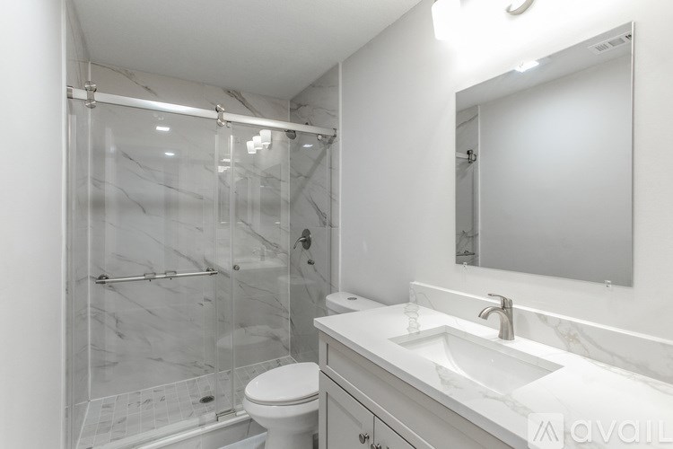 A white bathroom with a marble sink and a walk-in shower.