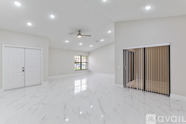 A spacious room with marble flooring and a ceiling fan.