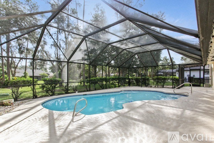 A pool under a glass roof with trees in the background.