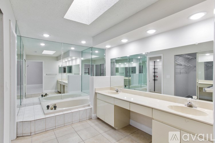 A bathroom with a glass shower stall, a bathtub, and a double sink vanity.