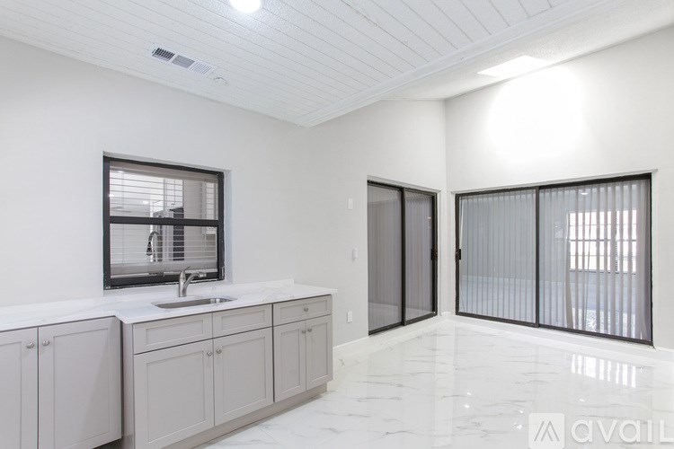 A modern kitchen with white cabinets and a marble floor.