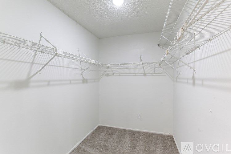 A man in a red shirt is taking a picture of a bathroom with two sinks.