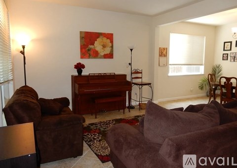 A living room with brown couches and a piano.