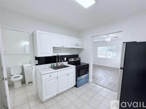 A kitchen with white cabinets and black appliances.