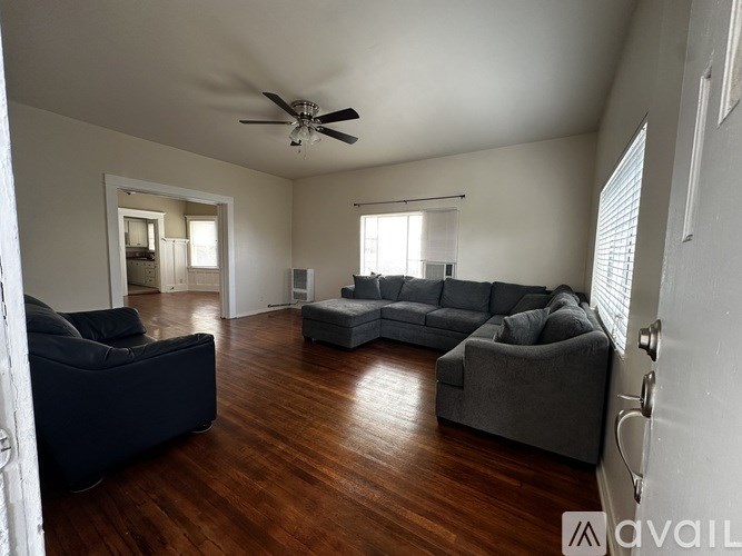 A spacious living room with a dark blue sofa and a grey sectional sofa.