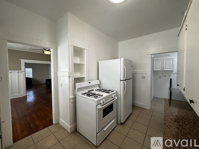 A kitchen with white appliances and a brown floor.