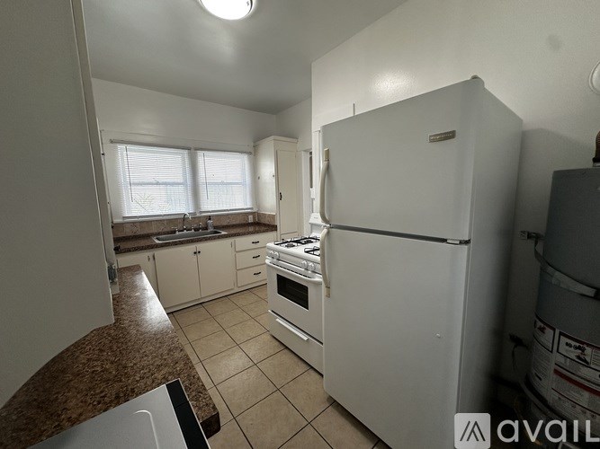A kitchen with white appliances and brown countertops.