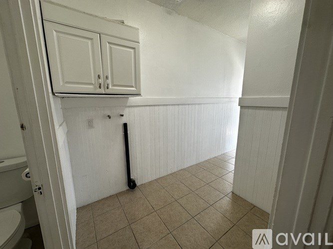 A white bathroom with a toilet and a white cabinet.