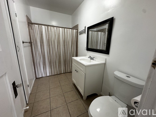 A bathroom with a toilet, sink, and shower curtain.