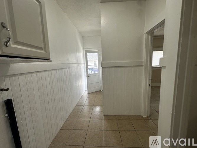 A long hallway with white walls and tile flooring.