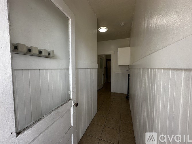 A long white hallway with a door at the end.