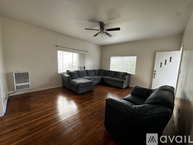 A living room with a black leather chair and grey couches.