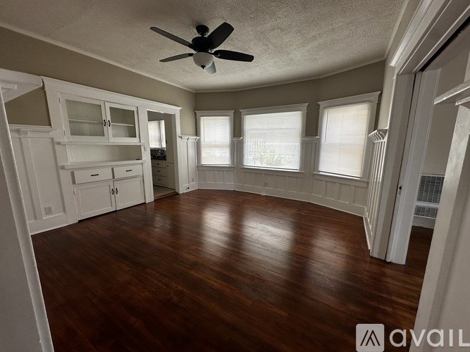 A room with a ceiling fan and wooden floors.
