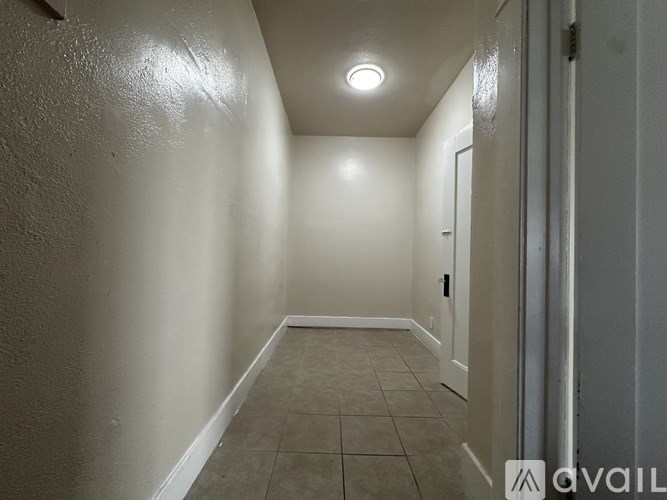 A long, narrow hallway with tiled flooring and white walls.