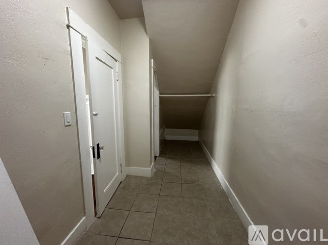 A hallway with a door on the left and a light on the wall.