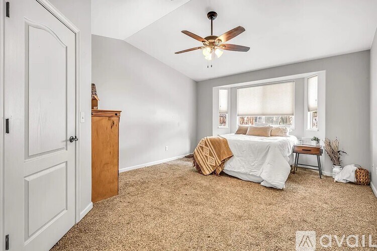 A bedroom with a bed, a dresser, and a ceiling fan.