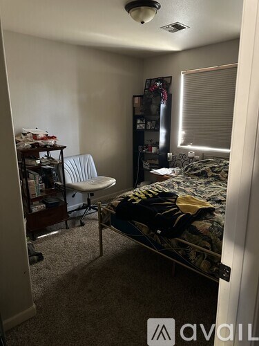 A bedroom with a bed, chair, and shelves.