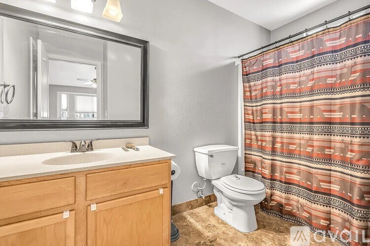 A bathroom with a toilet, sink, and shower curtain.