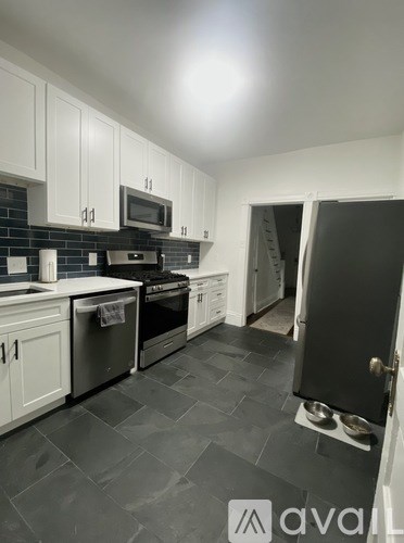 A kitchen with white cabinets and black countertops.