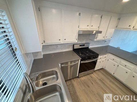 A kitchen with white cabinets and a stainless steel sink.