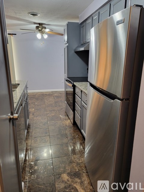 A kitchen with a stainless steel refrigerator and a ceiling fan.