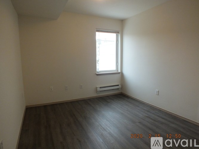 A room with a window and wooden floors is available for rent.
