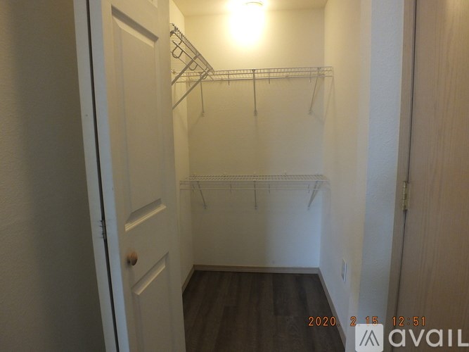 A small, empty room with a door on the left and a shelf on the right.