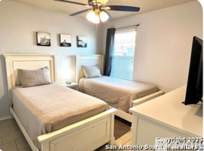 A bedroom with two beds and a ceiling fan.