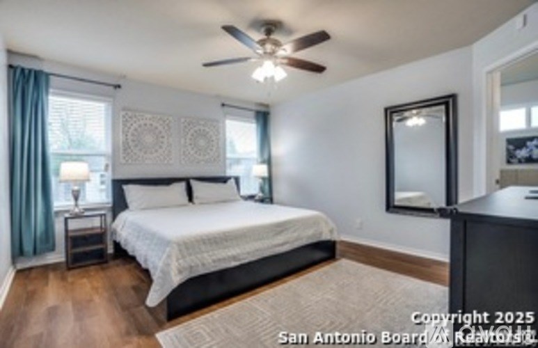 A bedroom with a bed, nightstand, and a ceiling fan.