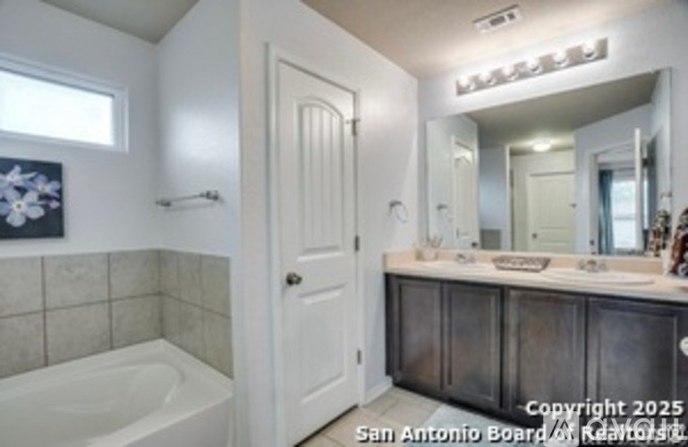 A bathroom with a white tub, sink, and door.