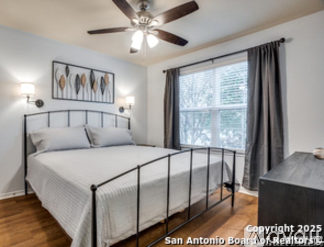 A bedroom with a white bed and a ceiling fan.