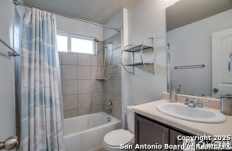 A bathroom with a white sink and a shower with a blue and white curtain.