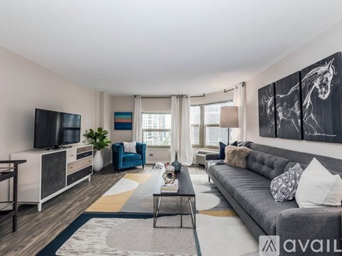 A living room with a grey couch, a coffee table, a television, and a painting on the wall.