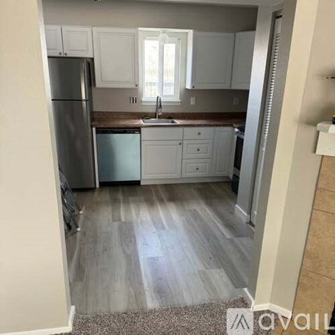 A kitchen with white cabinets and a refrigerator.