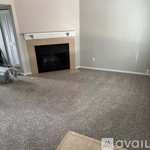 A living room with a fireplace and grey carpet.