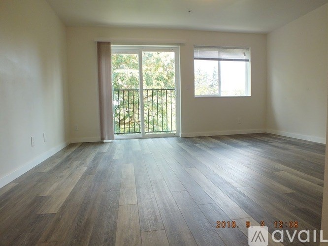 A room with wooden flooring and a window overlooking a balcony.