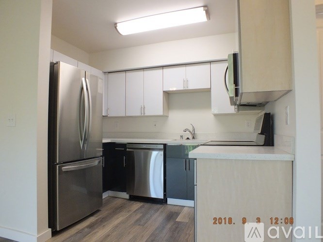 A kitchen with a stainless steel refrigerator and a wooden floor.