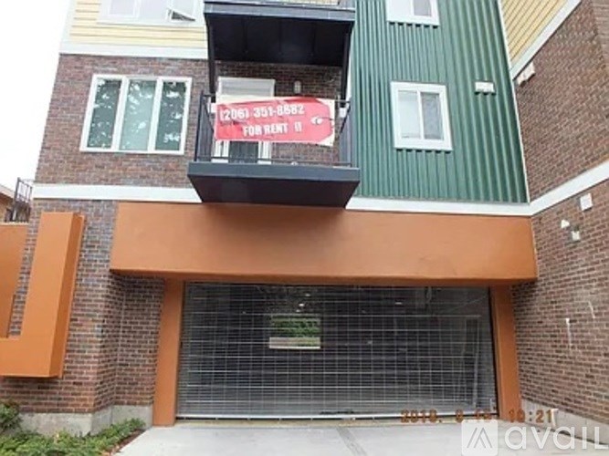 A building with a balcony has a sign that says "For Rent".