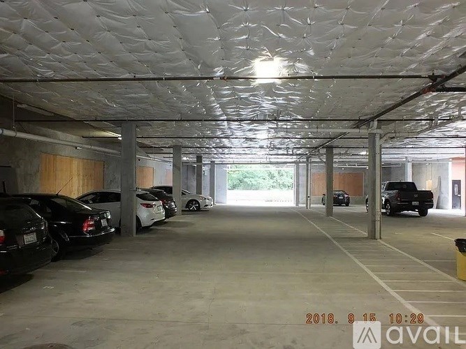 A parking garage with cars parked on the left side and a trash can on the right side.