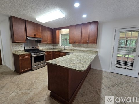 A kitchen with brown cabinets and a granite countertop.