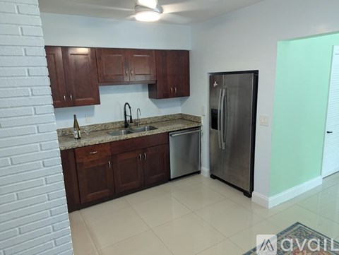 A kitchen with a refrigerator, sink, and cabinets.