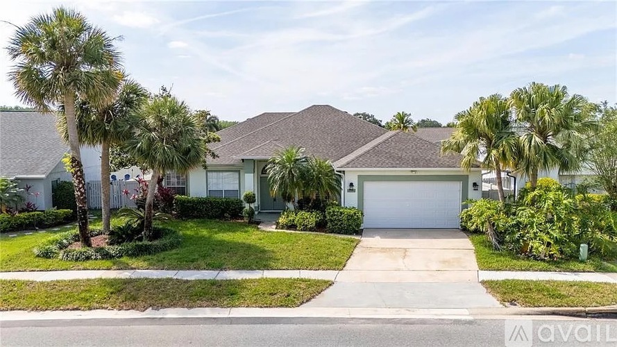 A house with a driveway and palm trees in front.