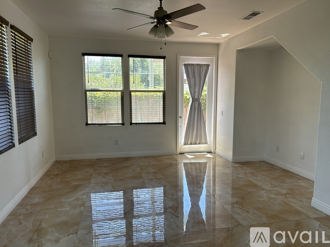 A spacious room with a ceiling fan, tiled flooring, and a sliding glass door.