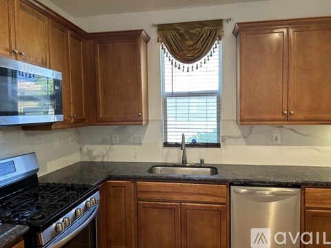 A kitchen with wooden cabinets and a stainless steel dishwasher.